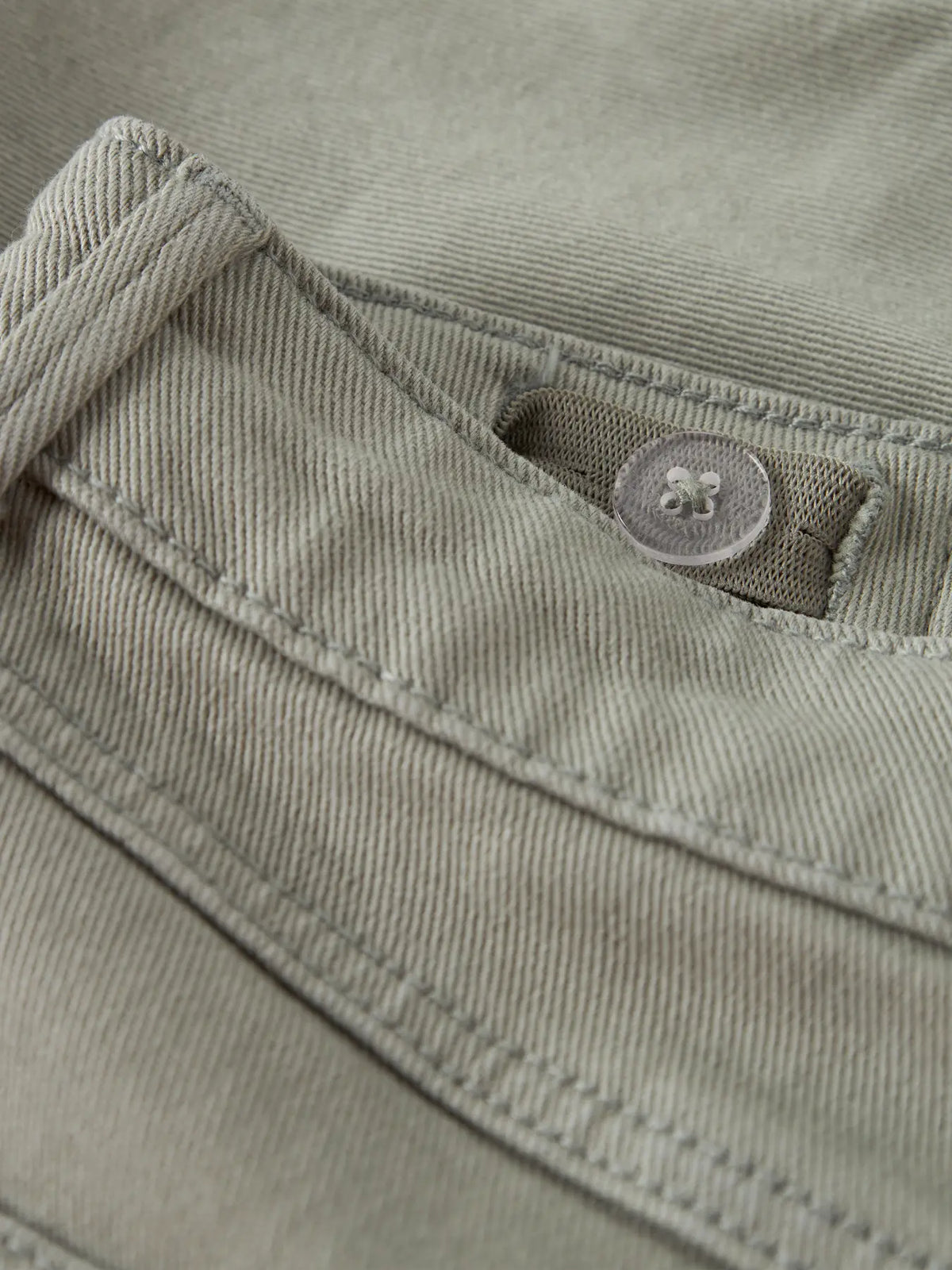 Detailaufnahme von grünen Chino Shorts mit Knopf von name it bei Bärechind in Winterthur, Zürich, Schweiz