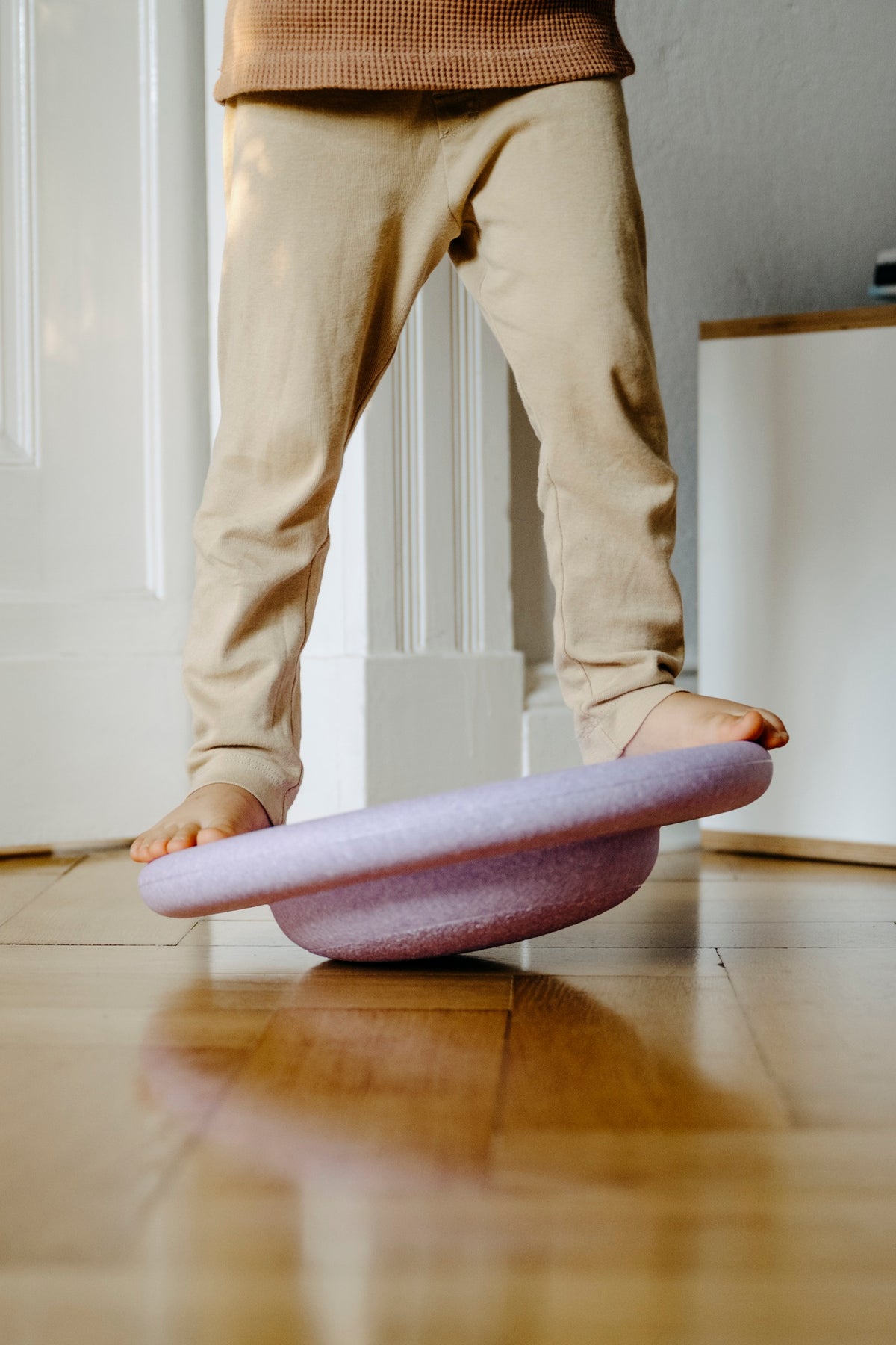 Kind balanciert auf helllila Stapelstein Board – ideal für drinnen und draussen