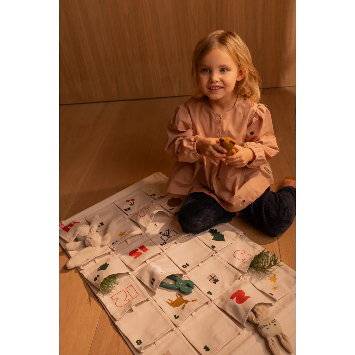 Kind spielt neben dem Liewood Babbo Adventskalender Sandy auf dem Tisch