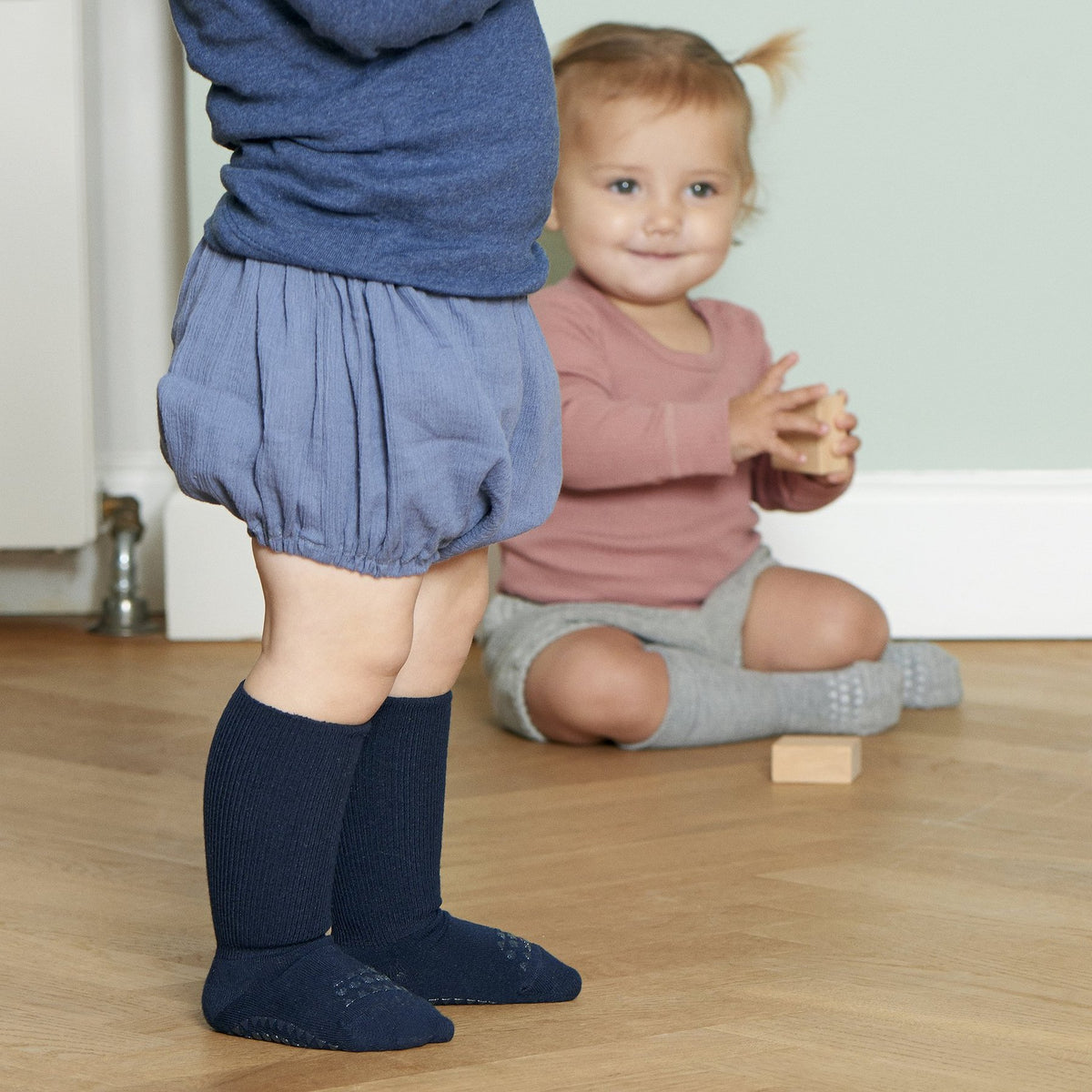 Baby in Bewegung mit navyfarbenen Anti-Rutsch-Socken von GoBabyGo – ideal für erste Schritte
