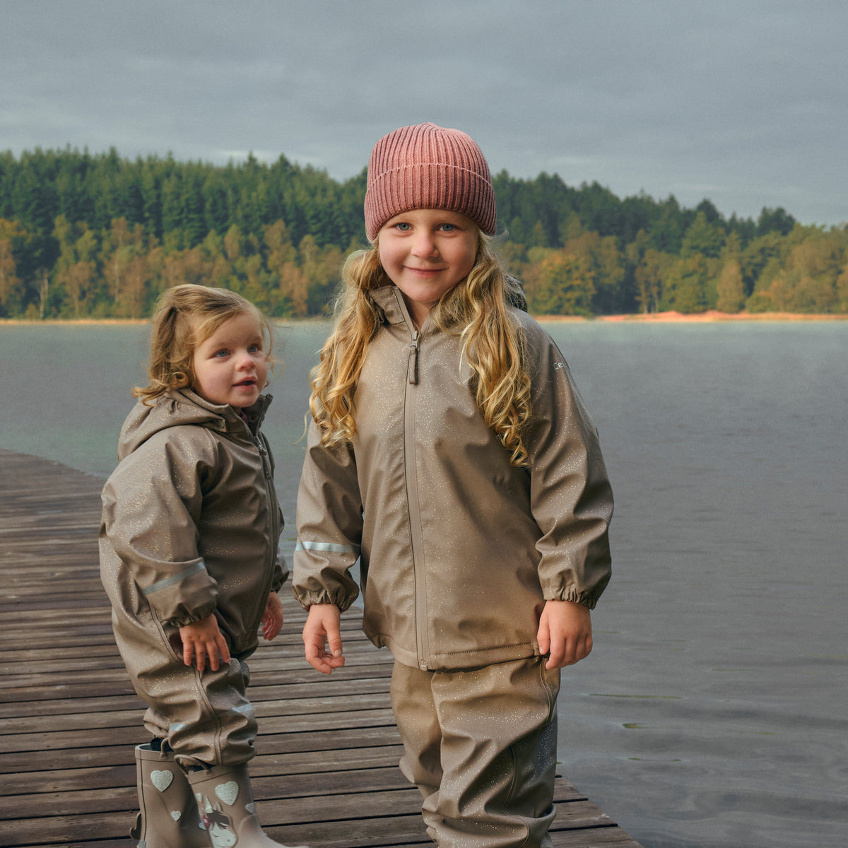 Kind trägt CeLaVi Regenset mit Muster in Fungi beim Spielen im Freien