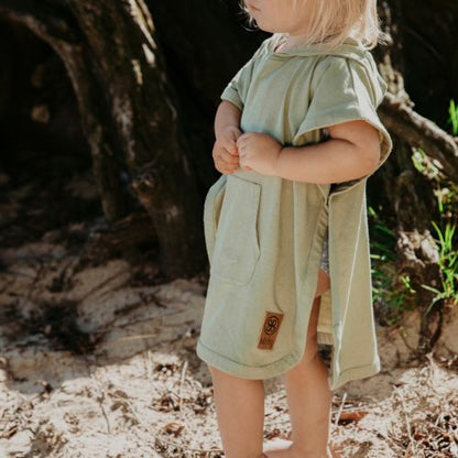 Kind trägt Cloby UV-Poncho in Olive Grün mit Kapuze und Vordertasche – Perfekter Sonnenschutz für Kinder mit UPF 50+. Ideal für Strand und Spielplatz. Jetzt im Kinderladen in Winterthur, Zürich, Schweiz erhältlich