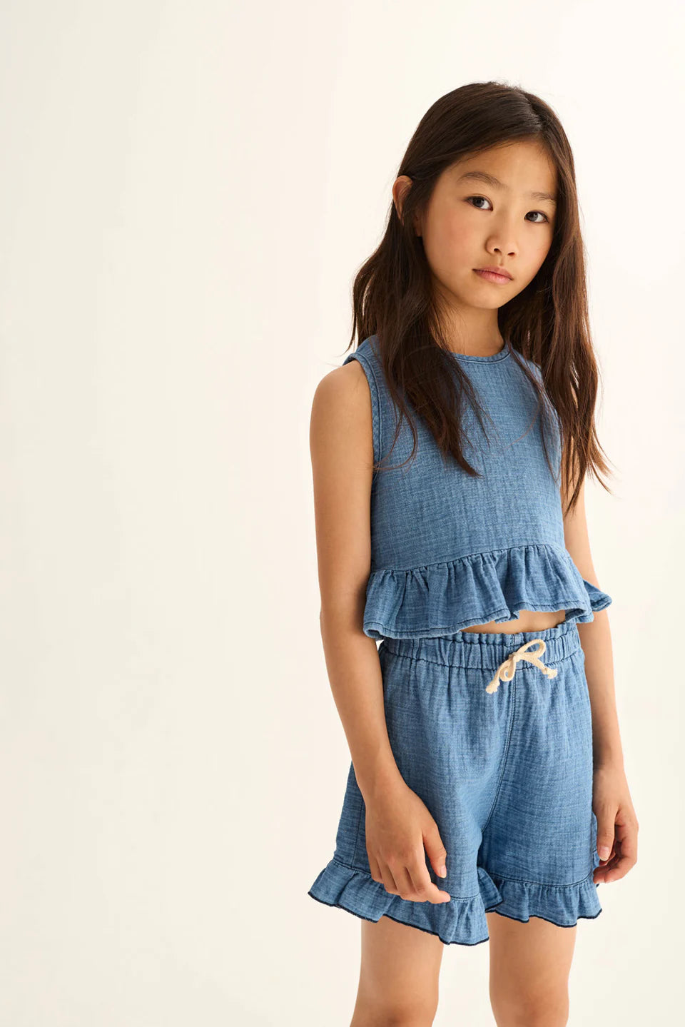 Kind trägt blaue Cozmo Shorts Isla aus Denim-Musselin – bequeme Sommer Shorts für Kinder in Winterthur