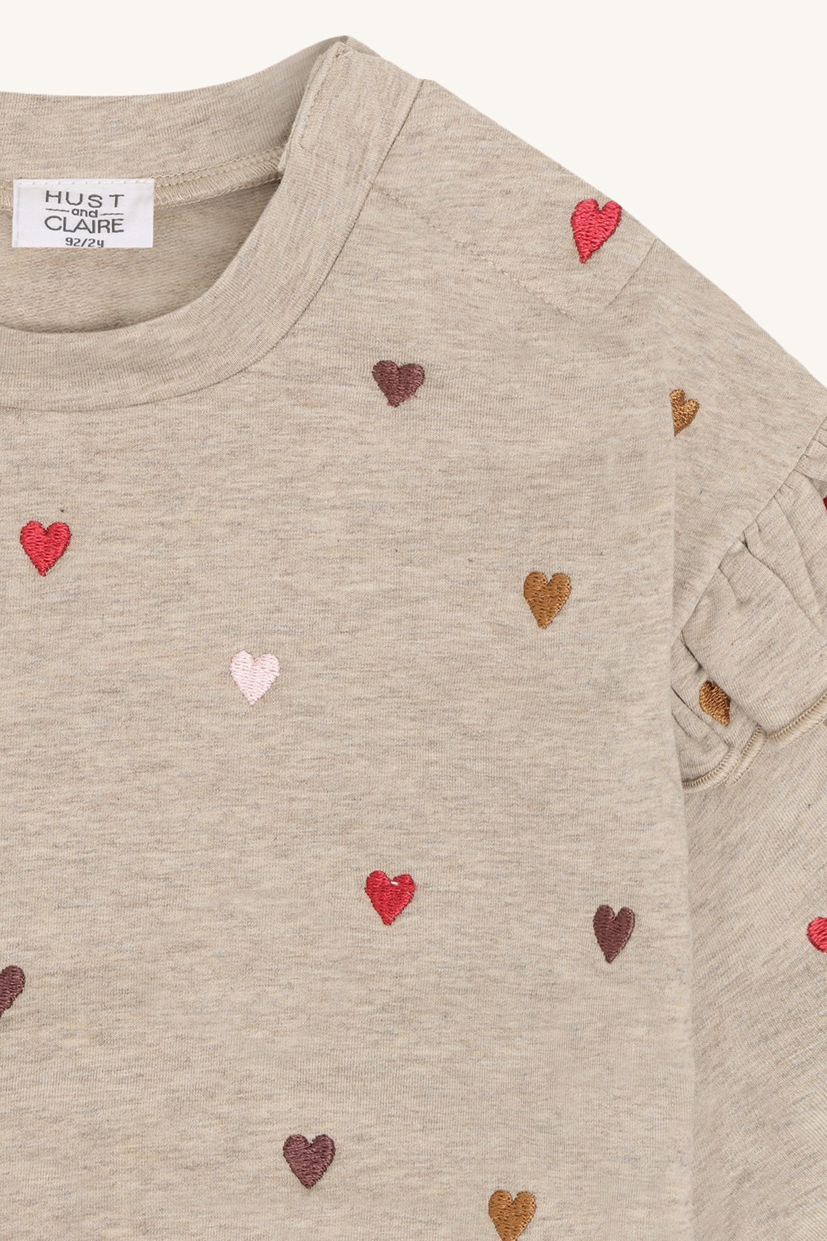 Herzstickerei und Rüschen am Schulterdetail des Langarmshirts im Nahblick