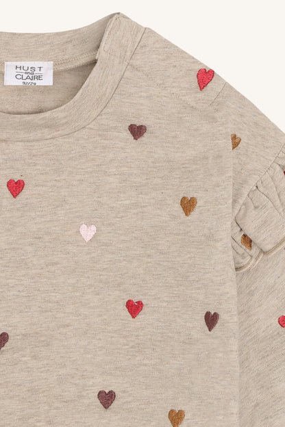 Herzstickerei und Rüschen am Schulterdetail des Langarmshirts im Nahblick