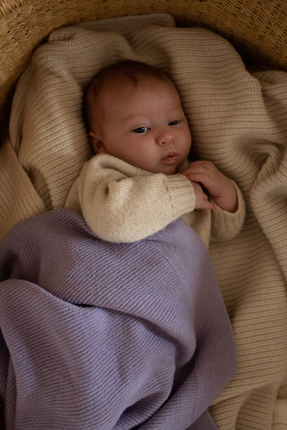 Baby eingekuschelt in Hvid Merino Babydecke Gusto in Lilac, erhältlich im Bärechind in Winterthur, Zürich Schweiz.