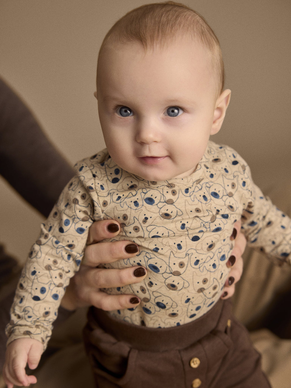 Baby trägt Minymo Body in Beige Melange