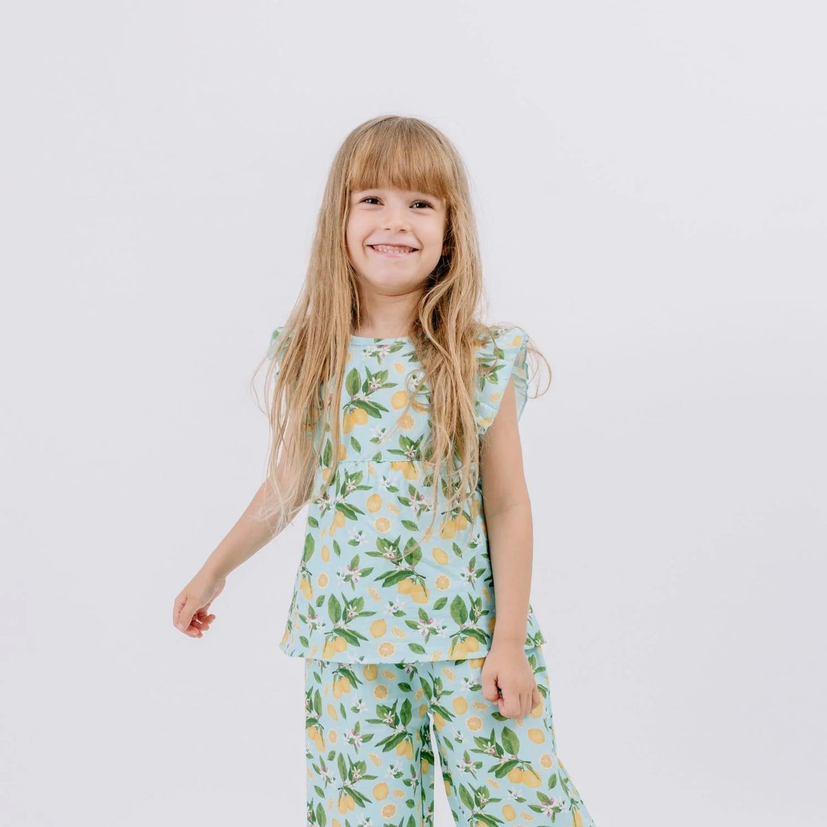 Kind trägt Walkiddy Citrus Bloom Bluse mit Zitronen Muster aus Bio Musselin – erhältlich bei Bärechind Winterthur Zürich Schweiz.