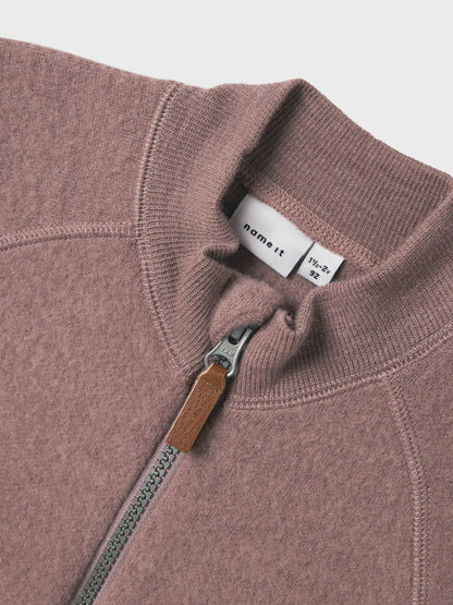 Nahaufnahme vom Reissverschluss und Kragen eines rosa Wollfleece-Jäckchens für Kinder.